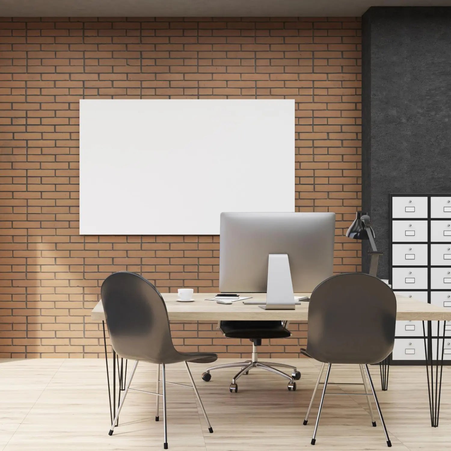 Modern office setup with a desk, chairs, and computer equipment against a brick wall.